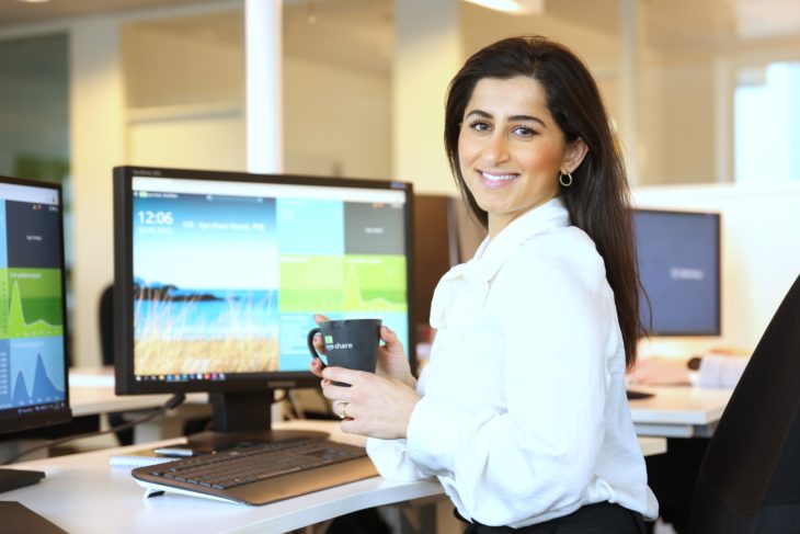 Solution Consultant, Lilas Warda, sitting infront of computer smiling