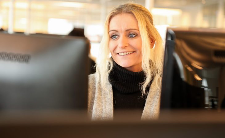 Lillian Olsen from Capture Services smiling infront of computer screen
