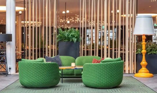Quality Hotel Airport Gardermoen hotel lobby with green chairs, yellow lamp and wooden wall details