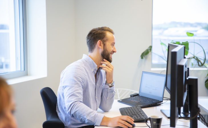 Eimund, Eye-share employee smiling in front of computer in office environment