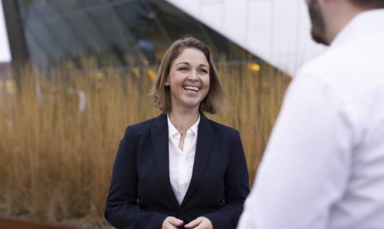 Dina Drehn, Director of Dep. Oslo smiling outside office building.